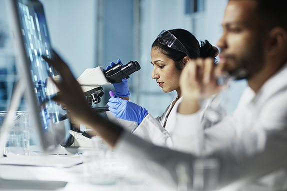 Researchers in laboratory at computer and microscope